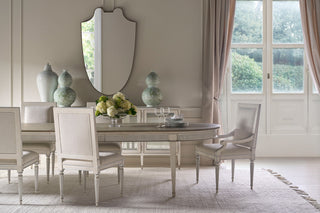 Dining room with a table set for four, decorative vases, and a large mirror.