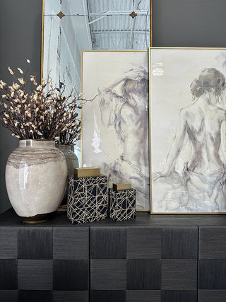black credenza decorated with a neural vase, two square jars and two pieces of artwork